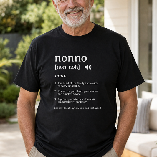 A man wearing a black graphic t-shirt with a white printed dictionary definition of the word 'nonno' on the chest, set against a blurred outdoor patio background.