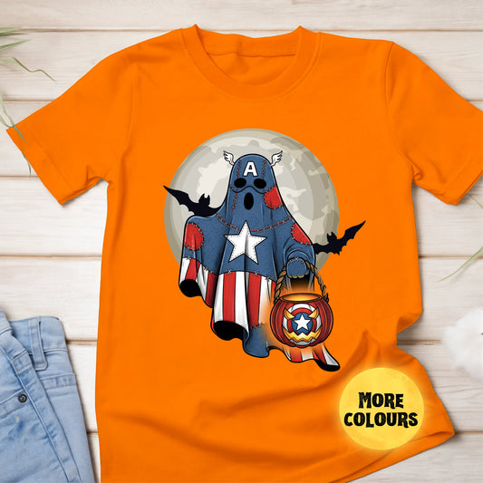 Orange t-shirt with a ghost in a superhero costume holding a pumpkin lantern on a wooden surface.