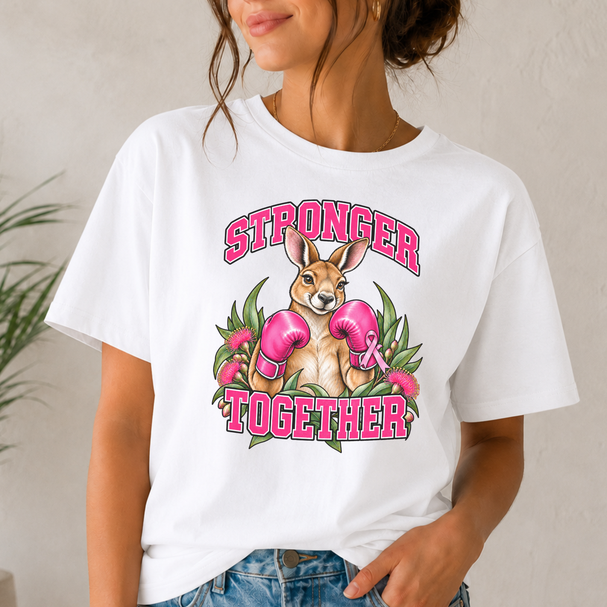 Woman wearing a Stronger Together kangaroo breast cancer awareness shirt with pink boxing gloves